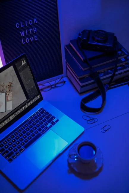 Back view of crop anonymous male freelancer sitting at table and working on project on laptop in light room in daytime